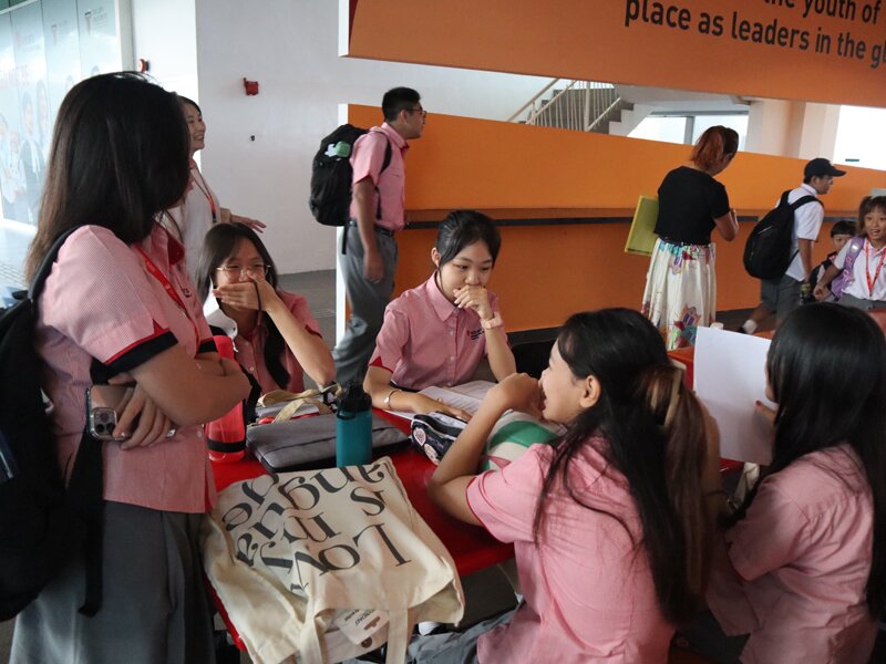 A group of Secondary school students having a chat in the cafeteria before the school begin for Term 3.